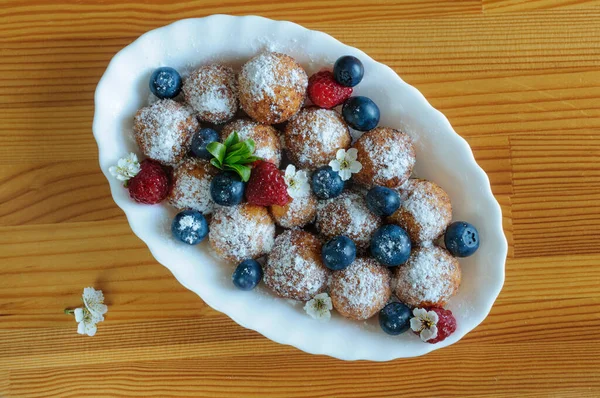 Sarı ahşap bir masada pudra şekeri ve böğürtlenli kremalı çörekler. Üst görünüm, yakın çekim, doğal ışık, seçici odak