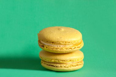 Yeşil arka planda iki tatlı sarı makroon. Kopyalama alanı ile seçmeli odak