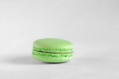 Gri arka planda bir yeşil makaron. Tatlı Fransız kurabiyeleri. Kopyalama alanı olan gün ışığı