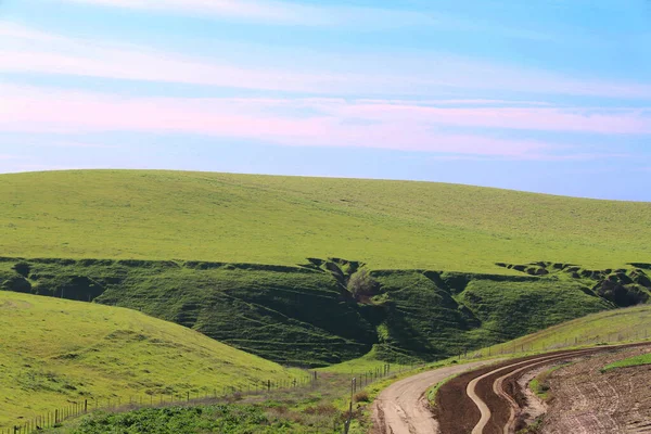 a green hills farm farmland canyon land dirt road blue sky agricultural landscape background