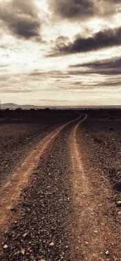 Dikey bir çöl macerası karanlık, boş bir siluet akşamın alacakaranlığı toprak yol karamsar sepya manzarası.