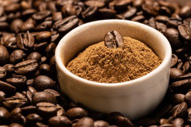 Kahve çekirdeğinin arka planında beyaz bir seramik kasede öğütülmüş tarçın.