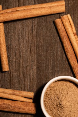 Beyaz bir seramik kasede ince bir tarçın. Tarçın, logo veya metin koymak için negatif alana sahip koyu bir arkaplana yapışır.