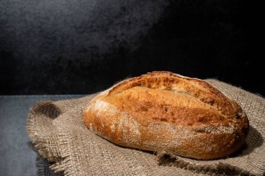 Freshly baked homemade bread on a dark concrete background. Copy space.