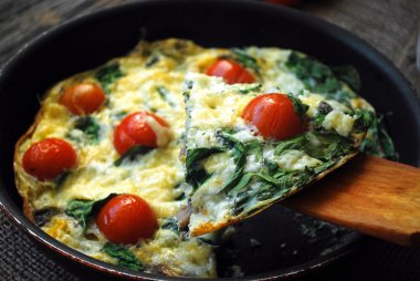 Frittata with cherry tomatoes, cheese and spinach. Close up