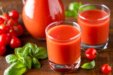 Ahşap masa arkasında bardak içinde domates suyu.