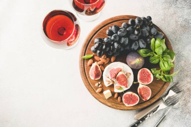 Camembert peyniri, incirli, üzümlü ve kadehli. Tahta servis tahtasının üstünde. Üst manzara, kopyalama alanı.