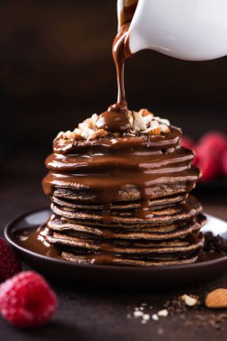 Çikolata soslu gözlemeler akıyor. Doğranmış fındık ve taze ahududu ile servis edilir.