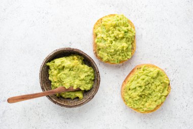 Gri beton arka planda ezilmiş avokado ile tost.