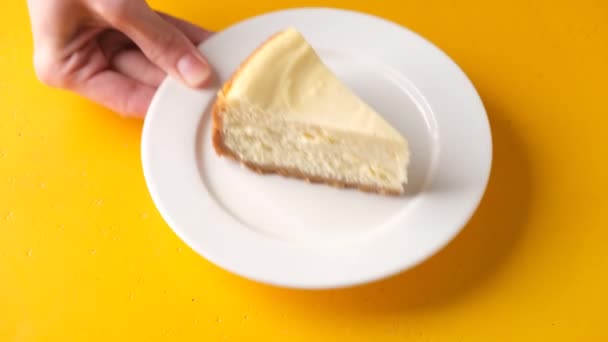ニューヨークチーズケーキの黄色の背景のスライスを提供しています 古典的なチーズケーキのおいしいスライス — ストック動画