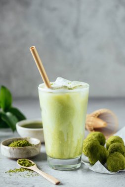 Matcha ice latte sağlıklı vejetaryen içeceği. Bardakta matcha enerji toplarıyla servis ediliyor. Metin veya tasarım için gri arkaplan kopyalama alanı