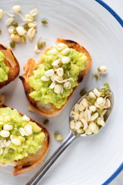 Avokado püresi ve mung fasulyesi filizli küçük tostlar.