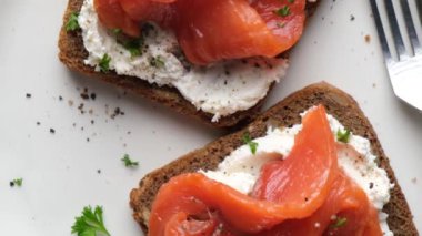 Krem peynirli tost ve maydanozla süslenmiş tuzlu somon balığı. Lezzetli sağlıklı açık sandviç.