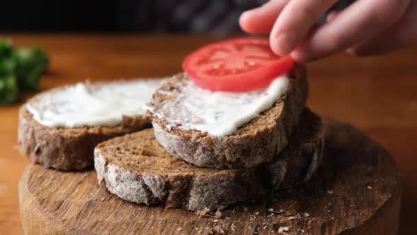 木製のサービングボード上のクリームチーズとトマトとトースト 健康的なチーズトマトオープンサンドイッチを作る — ストック動画