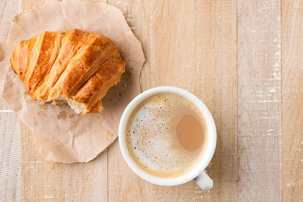 Tasse Kaffee Und Frisches Croissant Fehlt Ein Bissen Auf Holztisch — Stockfoto