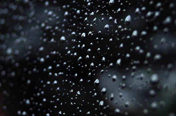 stock image The deep water droplets on the black surface and some of the water droplets are blurry