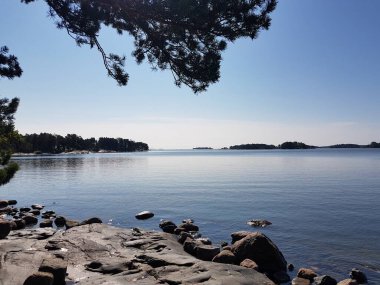 Yazın sonlarında deniz, kayalar ve ağaçlarla manzara.