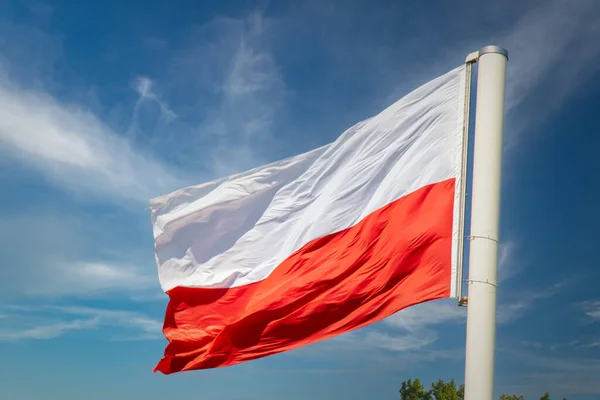 Polish flag against the background of the blue sky