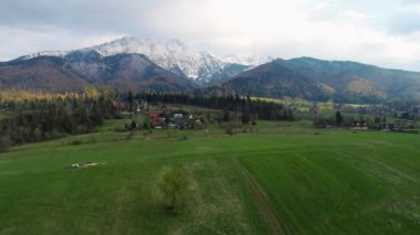 Karla kaplı yüksek dağ sıralarının havadan görünüşü. Tatra dağlarında güneşli bir gün ve yeşil ağaçların ve kayalık dağların manzarası. Yeşil dağ vadisi ve karla kaplı dağlar. 