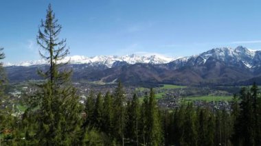 Karla kaplı yüksek dağ sıralarının havadan görünüşü. Tatra dağlarında güneşli bir gün ve yeşil ağaçların ve kayalık dağların manzarası. Yeşil dağ vadisi ve karla kaplı dağlar. 