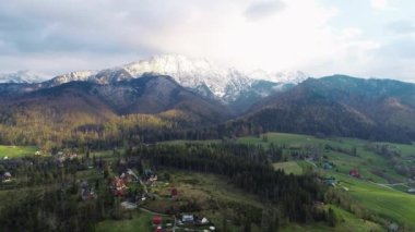 Karla kaplı yüksek dağ sıralarının havadan görünüşü. Tatra dağlarında güneşli bir gün ve yeşil ağaçların ve kayalık dağların manzarası. Yeşil dağ vadisi ve karla kaplı dağlar. 
