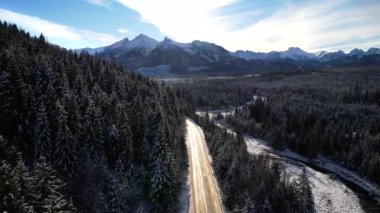 Kışın dağlık yol manzarası. Tatra dağlarında destansı, karlı beyaz kış. Yüksek kayalık dağlar ve temiz yol Polonya 'dan Slovakya' ya uzanan donmuş ormandan geçiyor.