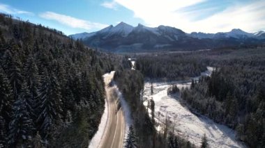 Kışın dağlık yol manzarası. Dağlarda destansı, karlı beyaz kış. Yüksek kayalık dağlar ve donmuş ormanda temiz bir yol.. 