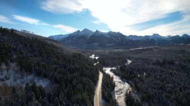 Kışın dağlık yol manzarası. Tatra dağlarında destansı, karlı beyaz kış. Yüksek kayalık dağlar ve temiz yol Polonya 'dan Slovakya' ya uzanan donmuş ormandan geçiyor.