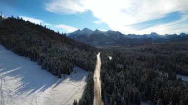 Kışın dağlık yol manzarası. Tatra dağlarında destansı, karlı beyaz kış. Yüksek kayalık dağlar ve temiz yol Polonya 'dan Slovakya' ya uzanan donmuş ormandan geçiyor.