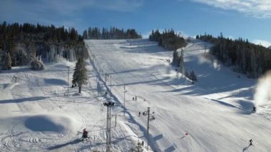 Kışın ünlü bir kayak merkezi, hava manzaralı. Kayak pisti ve yamaçta kayak yapan kayakçılar. Kayak asansörleri ve kış manzaralı güzel bir kayak merkezi. Taze beyaz kar ve çalışan kar topları..