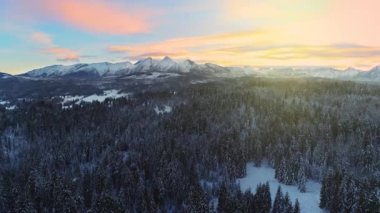 Kışın karla kaplı dağlar, hava manzarası. Kışlık dağ manzarası ve renkli günbatımı gökyüzü. Tatra yüksek dağları ve bozulmamış büyülü manzaralar.