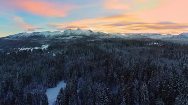 Kışın karla kaplı dağlar, hava manzarası. Kışlık dağ manzarası ve renkli günbatımı gökyüzü. Tatra yüksek dağları ve bozulmamış büyülü manzaralar.