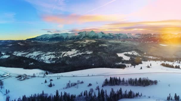雪の冬には山や山の道路 空中ビューキャップ 冬の山の風景とカラフルな夕日の空の空中ビュー タトラの高い山と魔法のように手付かずの風景 — ストック動画