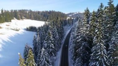 Kış aylarında dağlık yol manzarası ve sürüş arabası. Efsanevi, karlı beyaz kış ve karlı orman. Donmuş orman ve lüks sedan boyunca yol.