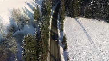 Kış aylarında dağlık yol manzarası ve sürüş arabası. Efsanevi, karlı beyaz kış ve karlı orman. Donmuş orman ve lüks sedan boyunca yol.