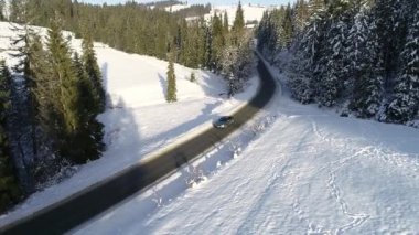 Kış aylarında dağlık yol manzarası ve sürüş arabası. Efsanevi, karlı beyaz kış ve karlı orman. Donmuş orman ve lüks sedan boyunca yol.