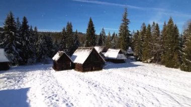 Sihirli kar beyazı kış manzarası. Dağlardaki kar kaplı kulübelerin havadan görünüşü. Kış ormanının ortasında karla kaplı güzel bir dağ evi ya da kulübe. Noel Bakışı.