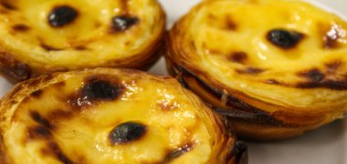 Pankart. Pastel de Belem. Ünlü Portekiz tatlı ikramı. Bir tabakta üç güzel Portekiz geleneksel pastası. Pastel de nata. Pastis de Belem.