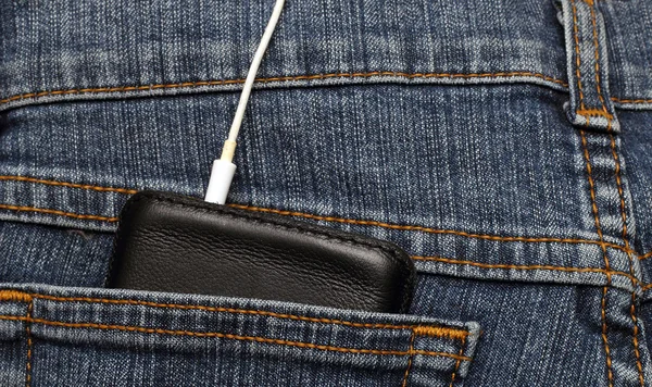 Mobiltelefon i fickan på jeans med hörlurar anslutna — Stockfoto