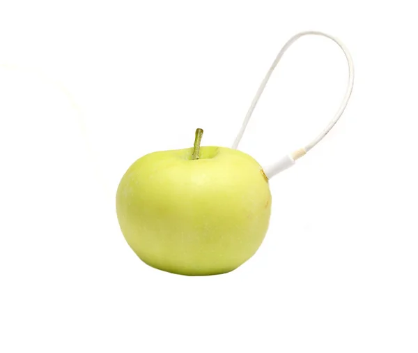 Зелене яблуко, в якому застрягли навушники — стокове фото