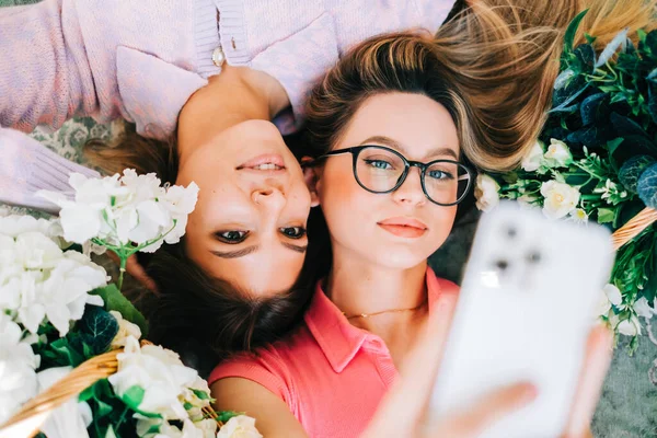 Retrato Dos Mujeres Caucásicas Atractivas Tumbadas Suelo Con Flores Haciendo — Foto de Stock