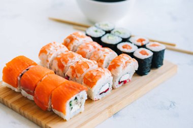 Bambu tahtasında suşi ruloları, Philadelphia, karidesler ve soya soslu maki, Japon yemekleri..