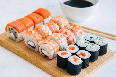 Bambu tahtasında suşi ruloları, Philadelphia, karidesler ve soya soslu maki, Japon yemekleri..