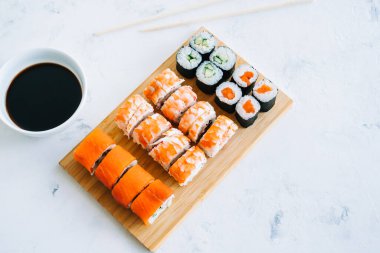 Bambu tahtasında suşi ruloları, Philadelphia, karidesler ve soya soslu maki, Japon yemekleri..