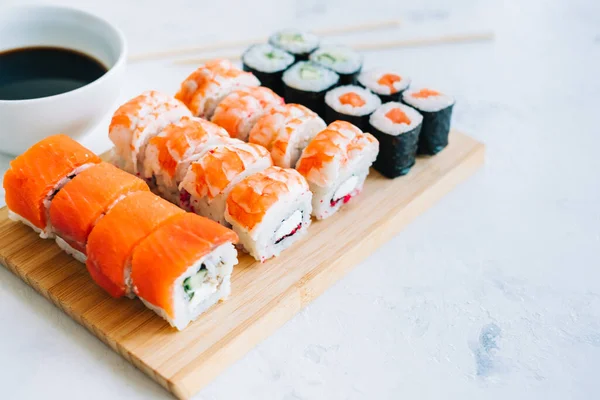 Bambu tahtasında suşi ruloları, Philadelphia, karidesler ve soya soslu maki, Japon yemekleri..