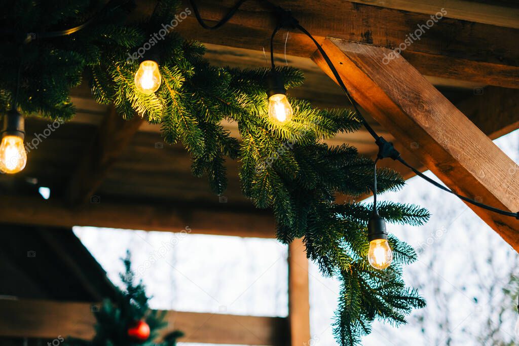 Christmas tree branches with garland on the backyard wooden roof.