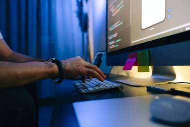 Mobil geliştirici bir bilgisayarda program kodu yazar, klavyede yazar, ev ofisinde programcı işi yapar.