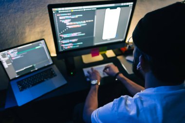 Genç adam mobil geliştirici bir bilgisayara program kodu yazar, programcı ev ofisinde çalışır..
