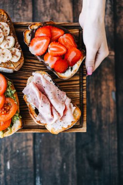 Lezzetli sağlıklı tostlar kahvaltı, öğle yemeği ya da atıştırmalıklar ellerinde tahta bir tahtanın üzerinde..