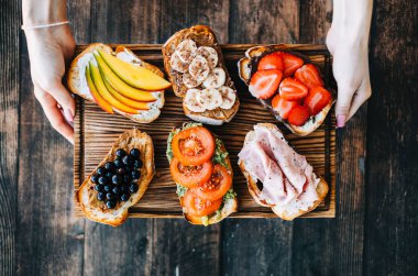 Lezzetli sağlıklı tostlar kahvaltı, öğle yemeği ya da atıştırmalıklar ellerinde tahta bir tahtanın üzerinde..